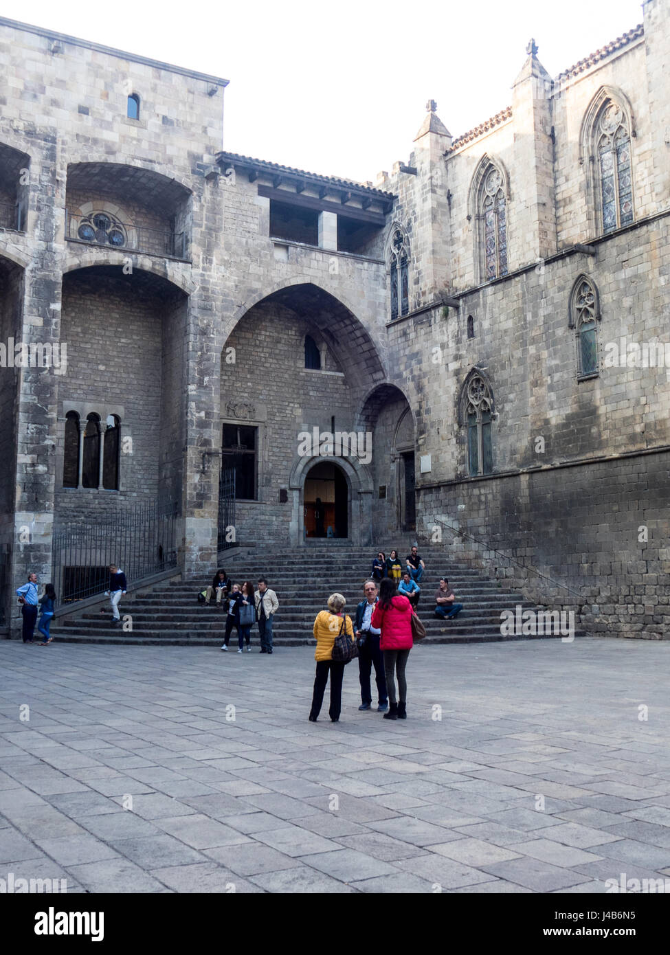 Gente sentada la escalinata del Saló del Tinell y la Capilla de Santa Águeda en la Plaça del Rei, Barcelona, España. Foto de stock