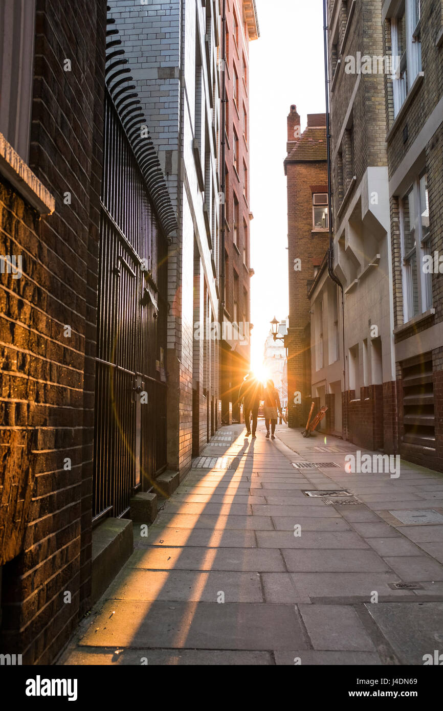 Pareja caminando por la calle estrecha hacia la puesta del sol,Lewisham Street, SW1,Londres,Inglaterra Foto de stock