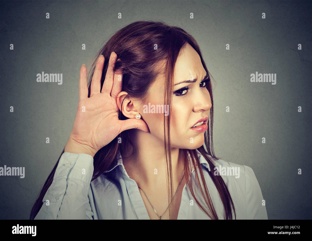 Mujer con gesto de la mano al oído escucha atentamente pidiendo hablar arriba Foto de stock
