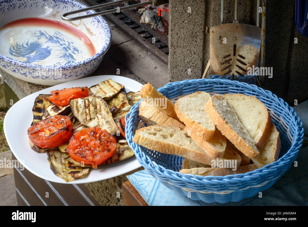 Un plato de tomates asados, calabacín y berenjenas y un pecho del pan para bruschetta Foto de stock