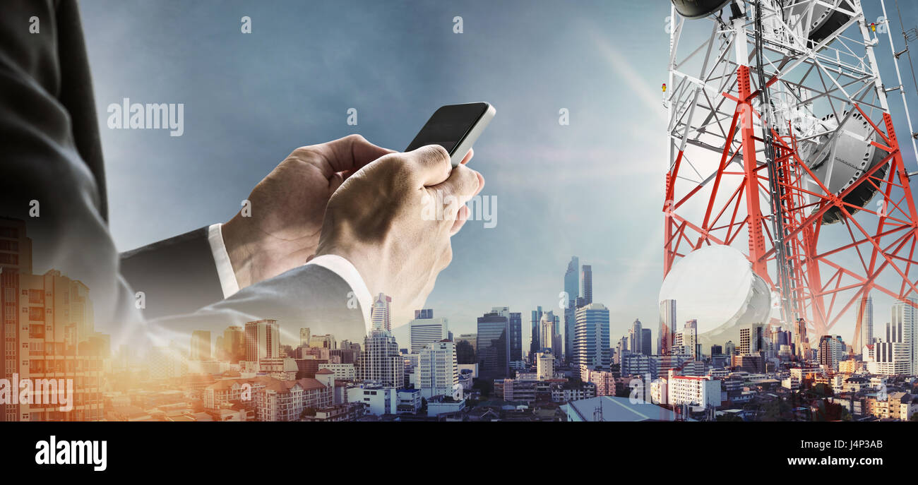 Empresario mediante smartphone con doble exposición moderna ciudad en Sunrise, y las torres de telecomunicaciones Foto de stock