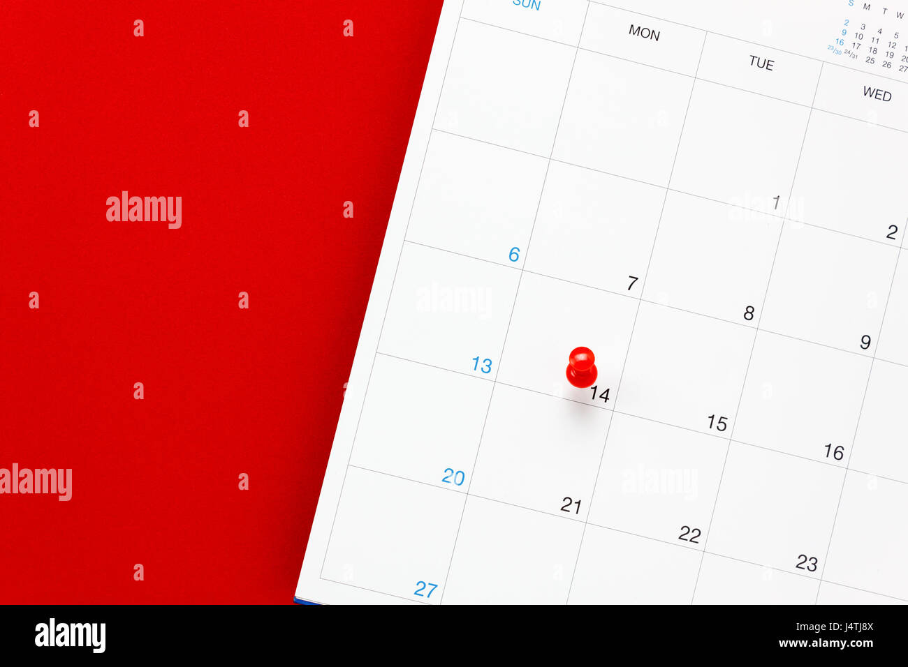 Vista superior del día de San Valentín el pin rojo marca en el calendario sobre fondo rojo. Foto de stock