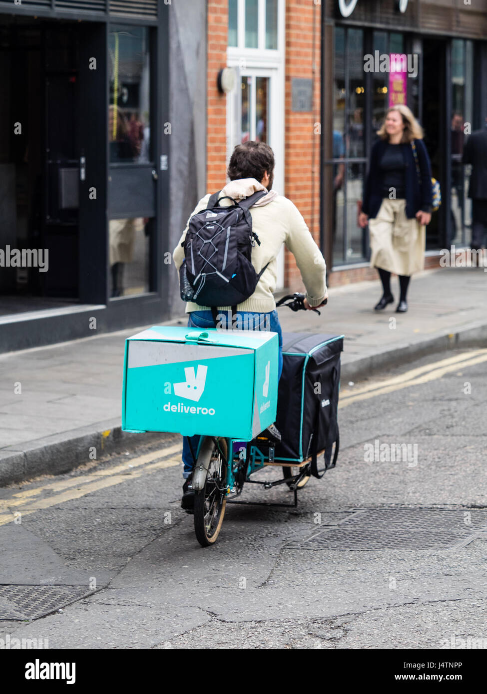 La entrega de alimentos Deliveroo courier entrega alimentos en una bicicleta de carga de gran capacidad. Foto de stock