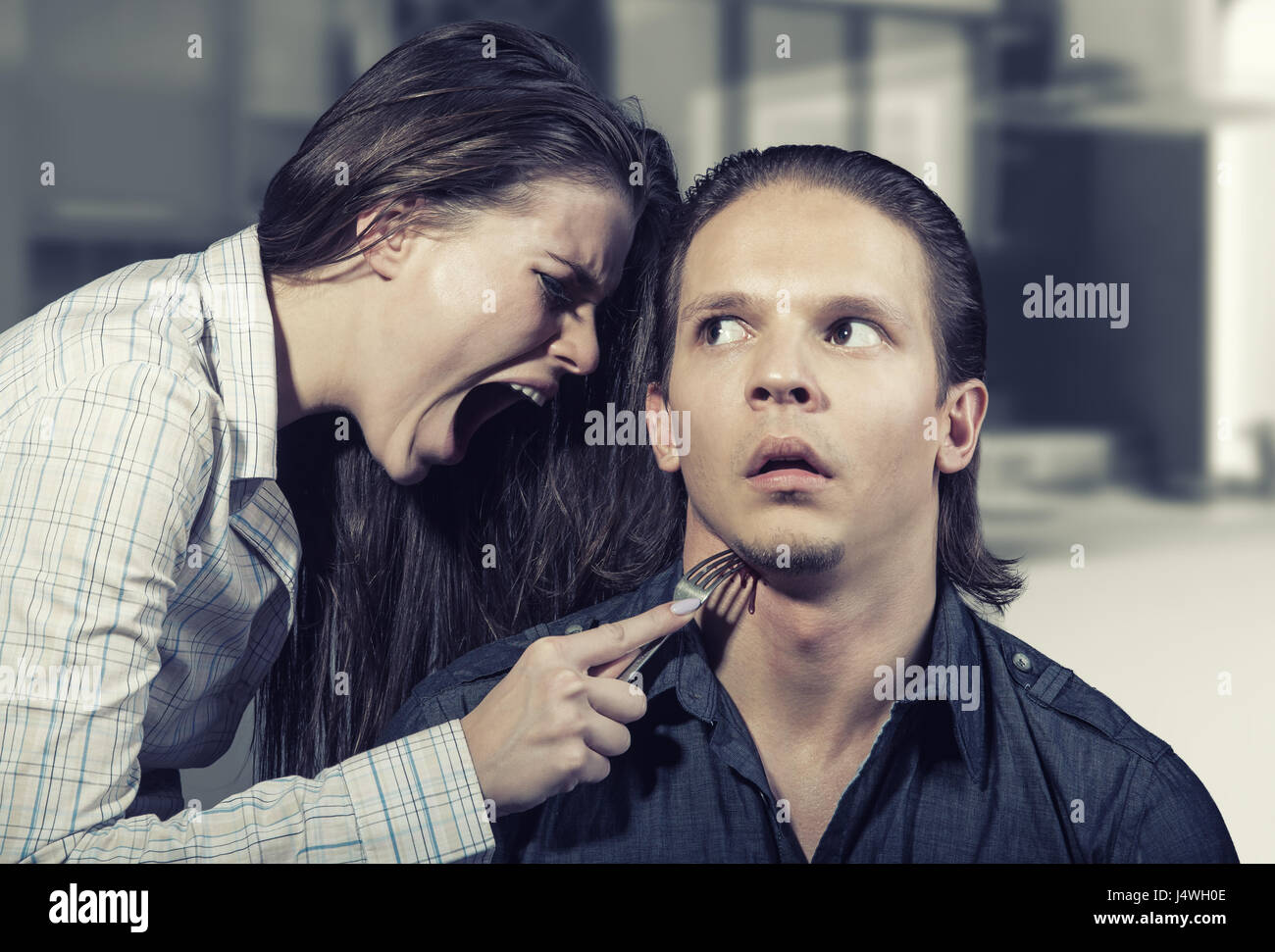 Disputa familiar. Mujer joven apuñala la garganta del marido. Foto de stock