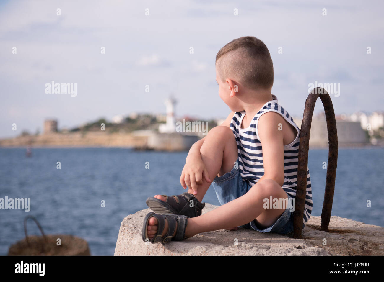 Soñar chico vestían camiseta y pantalones cortos, mirando a la distancia con telón de fondo de un del mar en verano Fotografía de stock - Alamy