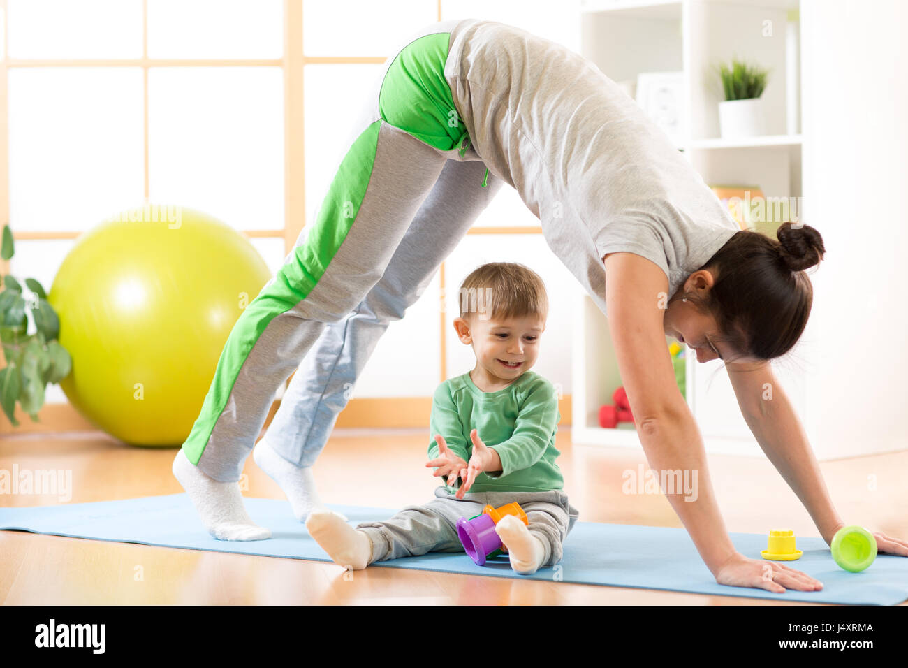 Madre haciendo yoga o ejercicios físicos con el bebé Foto de stock
