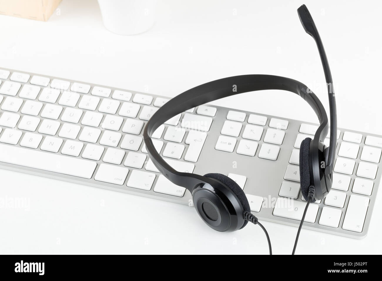 Equipo auricular con micrófono en el teclado del ordenador de mesa blanco - comunicación o helpcenter concepto Foto de stock