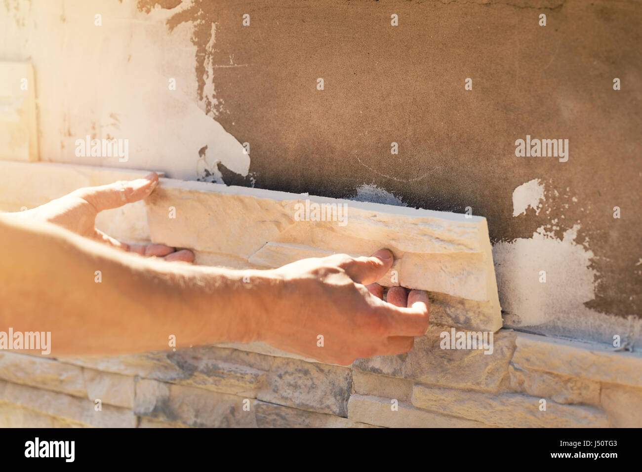 Instalación de baldosas de piedra decorativa del trabajador sobre la fachada de la casa Foto de stock