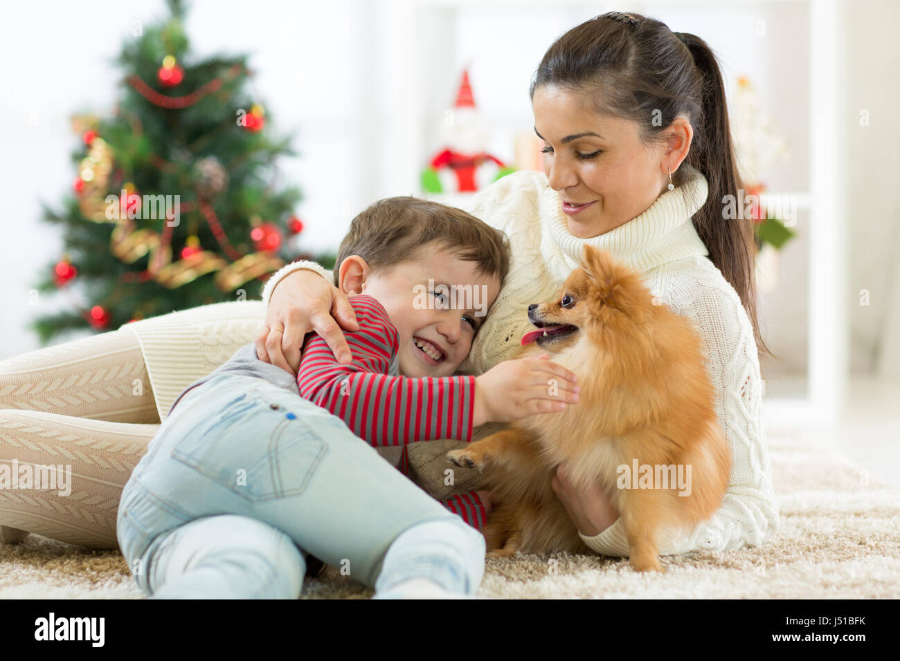 Familia sonriente y perro sentado por árbol de Navidad Foto de stock