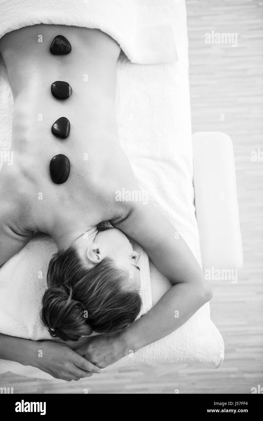 Joven recibe el masaje con piedras calientes Foto de stock