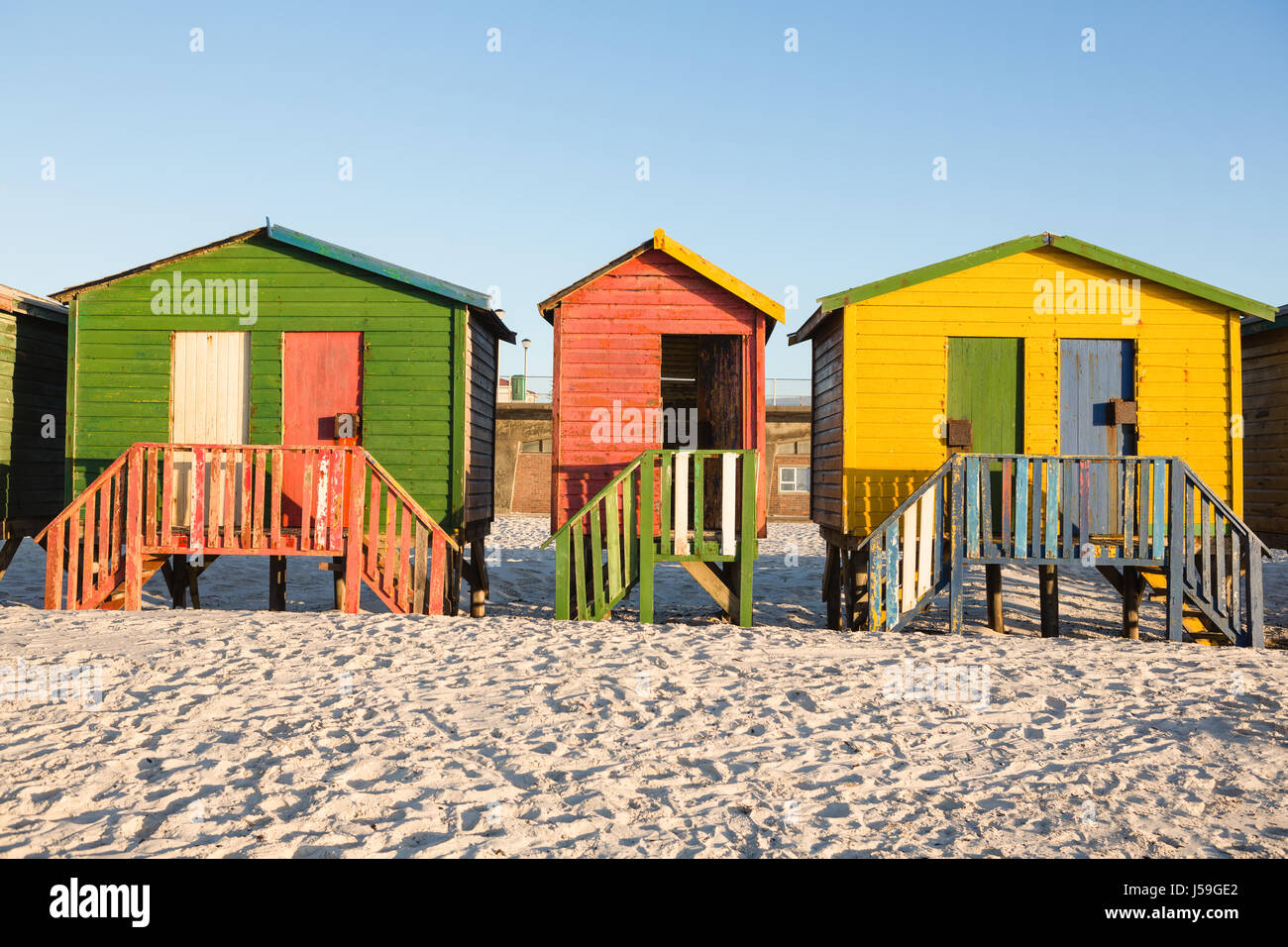 Cabañas multicolores sobre arena contra el cielo claro en la playa Foto de stock