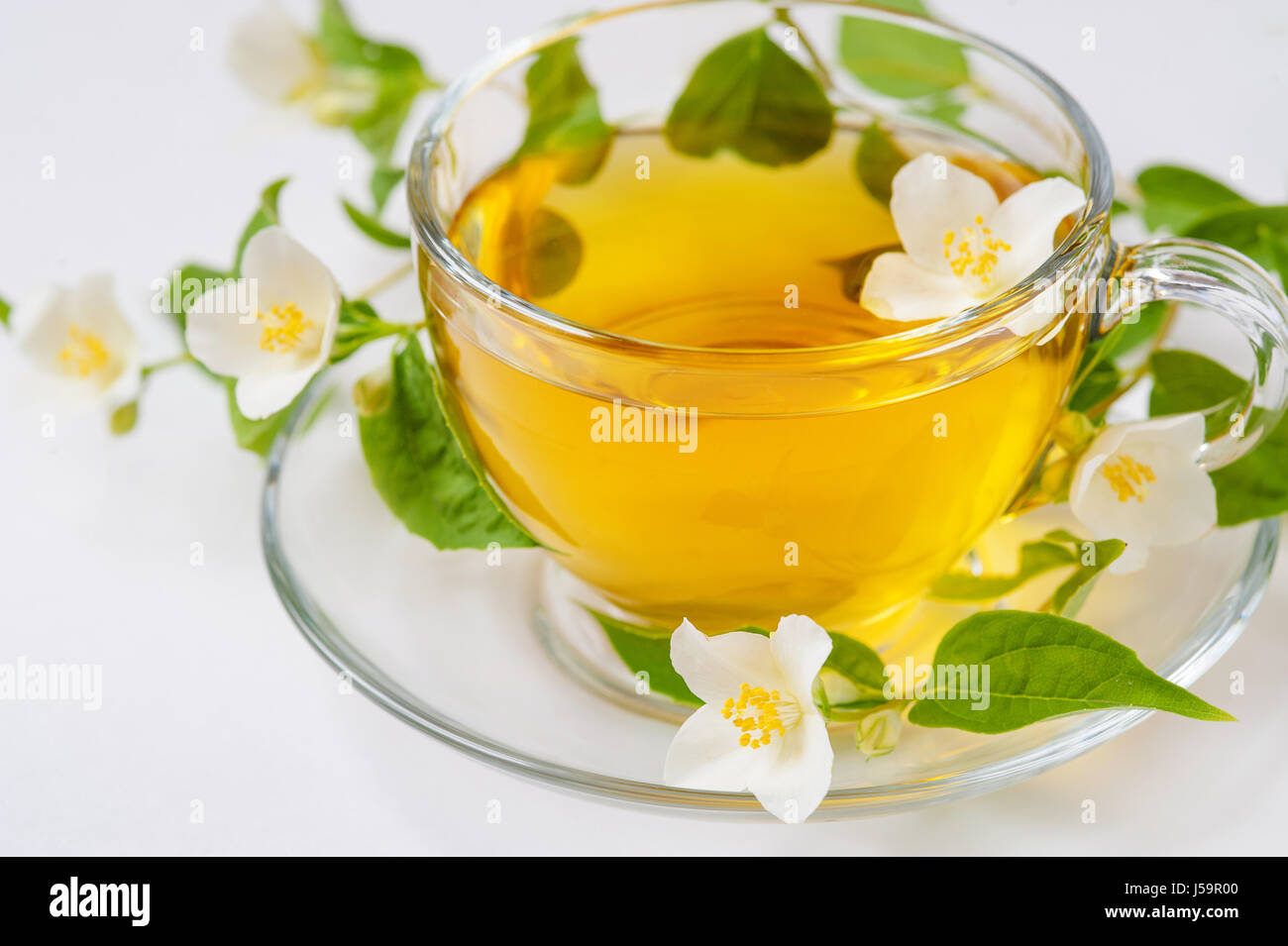 Una taza de té de jazmín con flores de jazmín sobre un fondo de madera Foto de stock