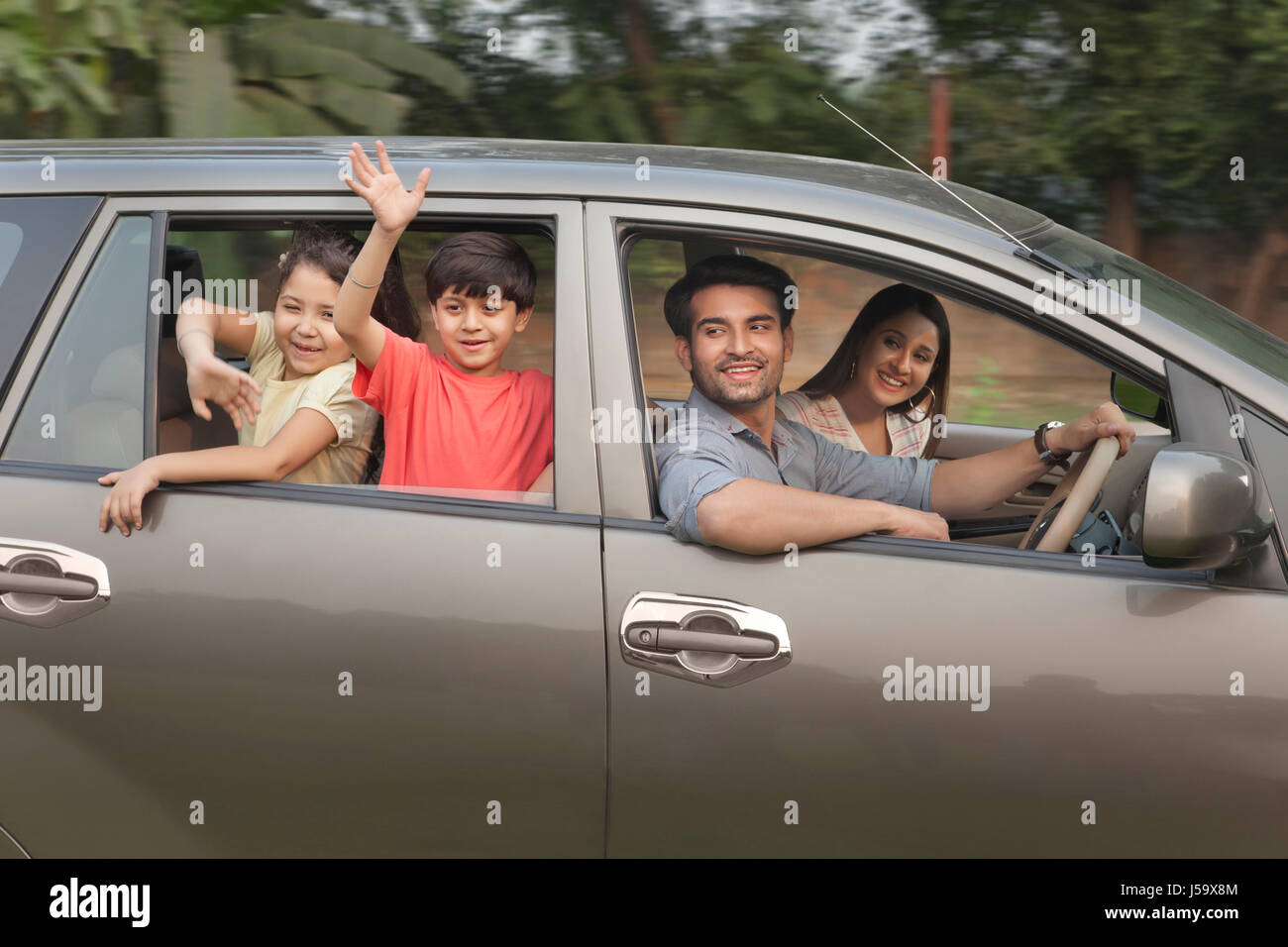 Los niños con padres agitando desde car window Foto de stock