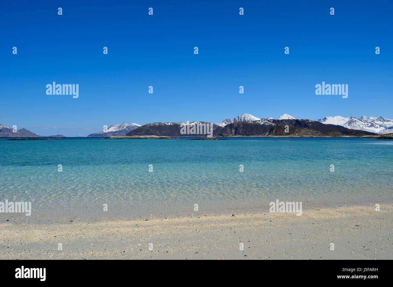 Blanco majestuoso primavera playa con montaña nevada islas en el mar en la isla de verano en el norte de Noruega. Foto de stock