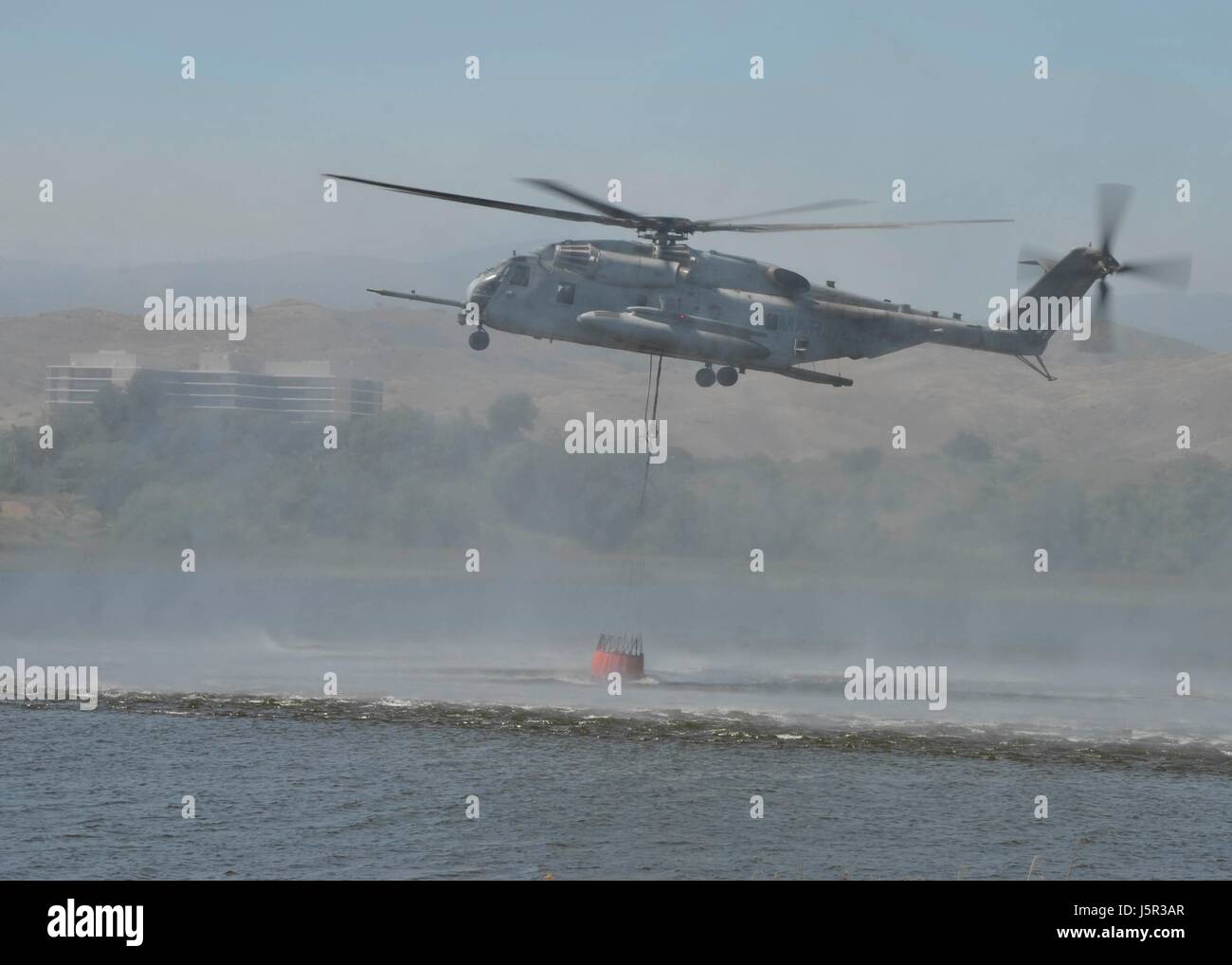 Un Semental de mar USMC helicóptero extrae agua del lago O'Neill suspendidas en bambi cubo durante un ejercicio de demostración de bomberos forestales en el Marine Corps Base Camp Pendleton, 4 de mayo de 2017 cerca de Oceanside, California. (Foto por Curtis D. Spencer /US Navy via Planetpix) Foto de stock