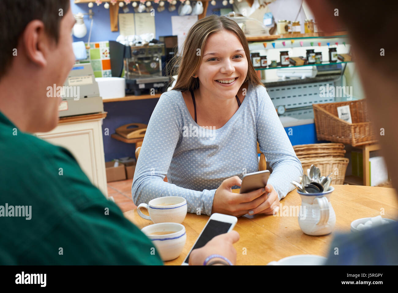 Grupo de Adolescentes reunión de amigos en el café y el uso de teléfonos móviles Foto de stock