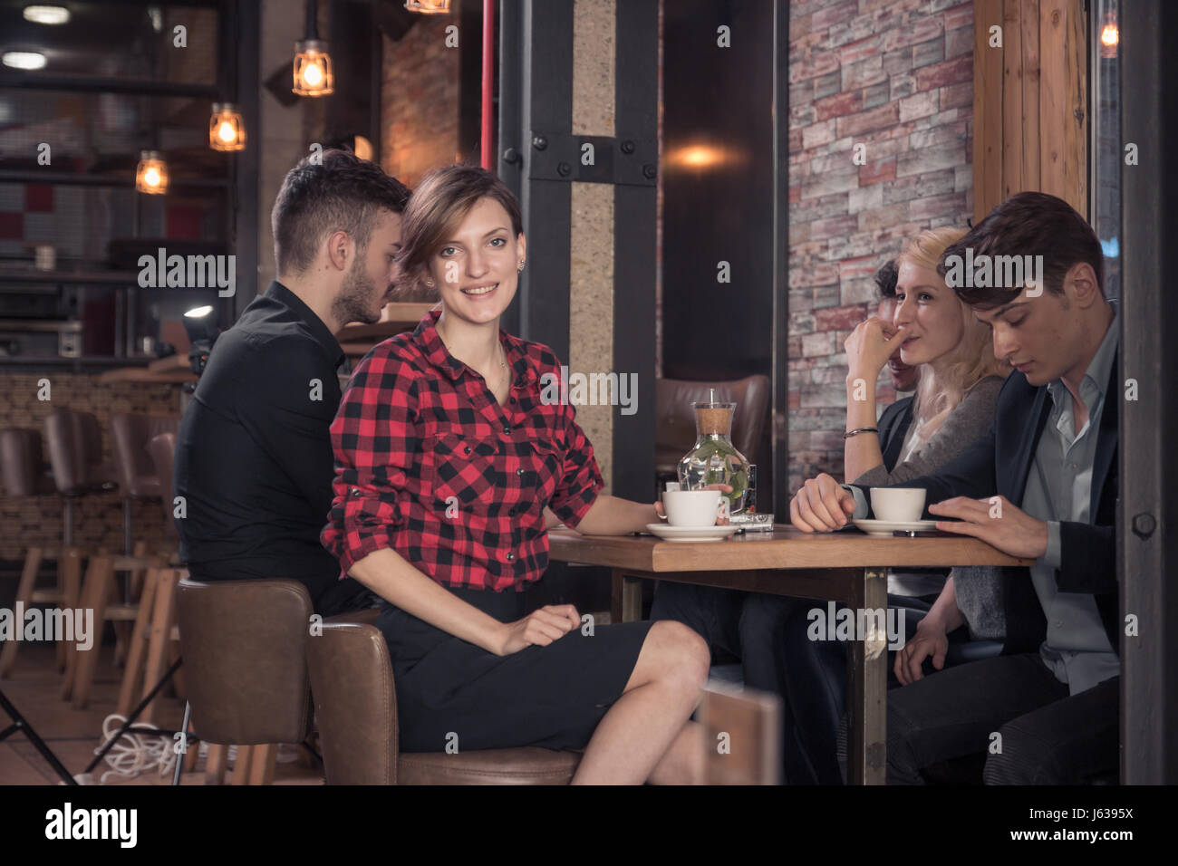 Los adultos jóvenes, pequeños grupos de personas, mesa y sillas, mesa de café, mujer mirando a la cámara, coffee shop Foto de stock