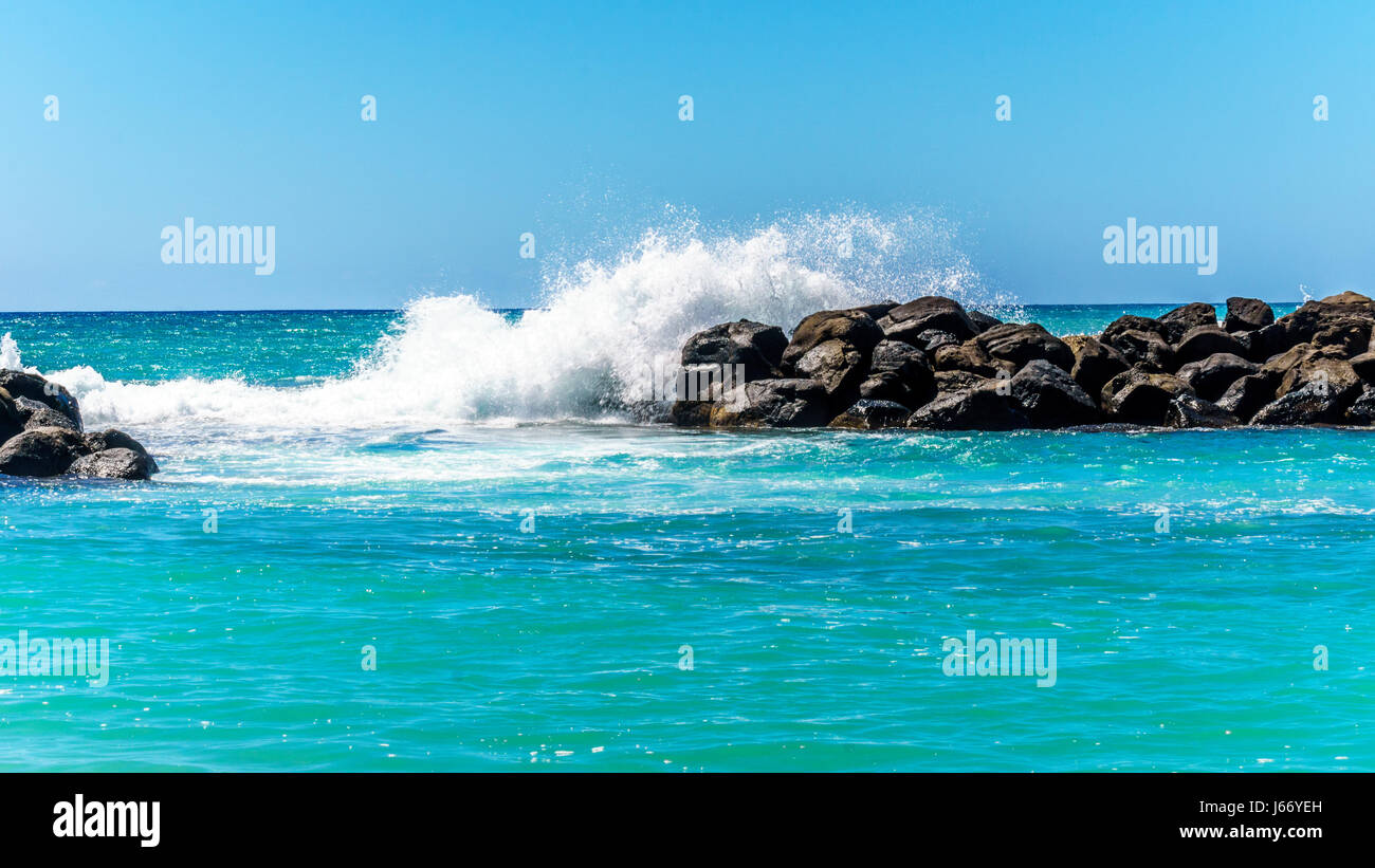 Olas rompiendo sobre las barreras que crean las lagunas de Ko Olina en la costa oeste de la isla hawaiana de Oahu. Las lagunas ideales para nadar Foto de stock