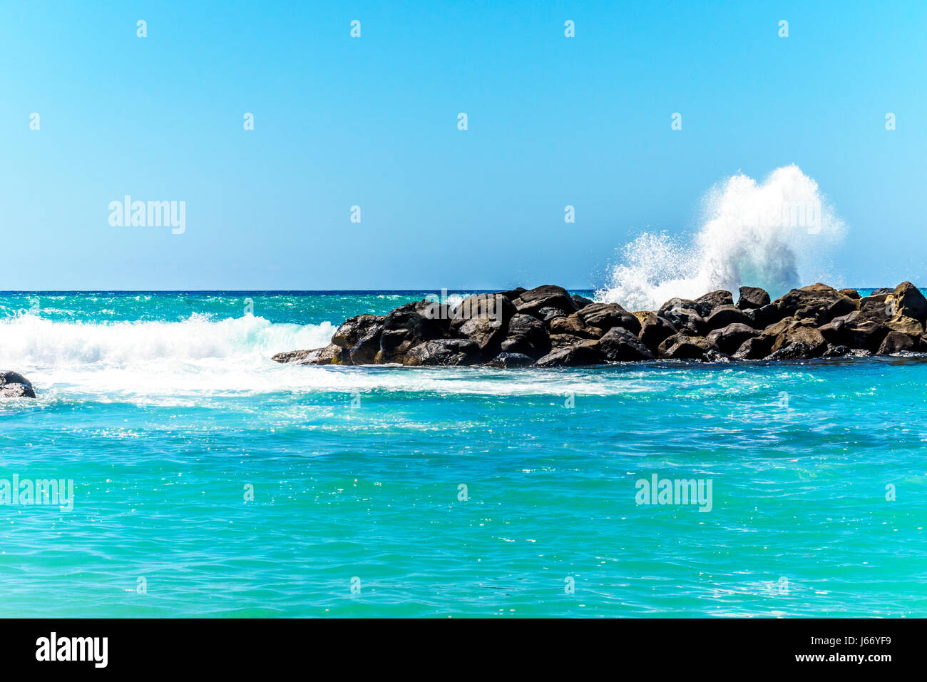 Olas rompiendo sobre las barreras que crean las lagunas de Ko Olina en la costa oeste de la isla hawaiana de Oahu. Las lagunas ideales para nadar Foto de stock
