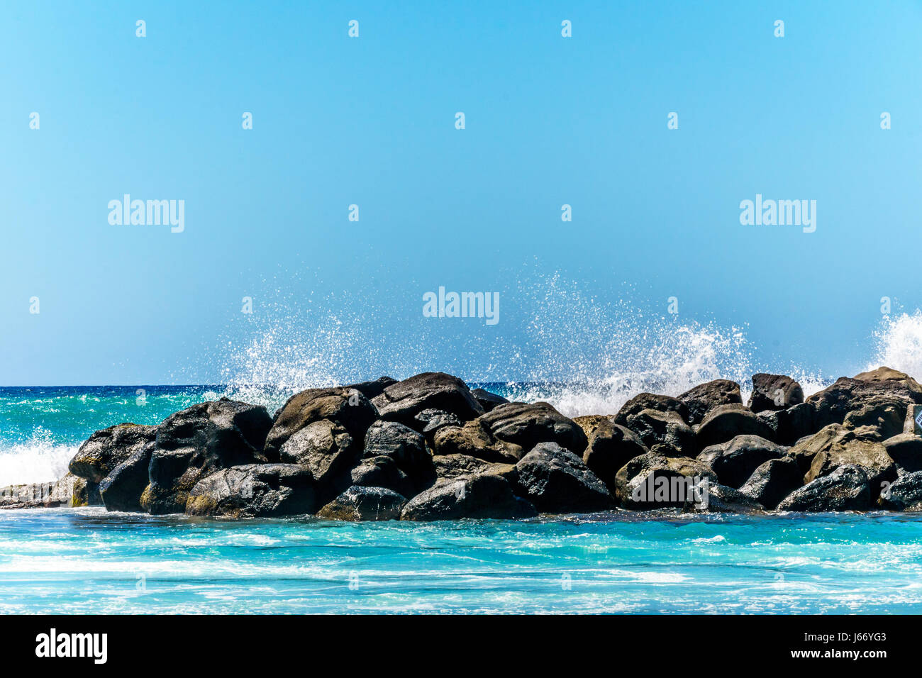 Olas rompiendo sobre las barreras que crean las lagunas de Ko Olina en la costa oeste de la isla hawaiana de Oahu. Las lagunas ideales para nadar Foto de stock