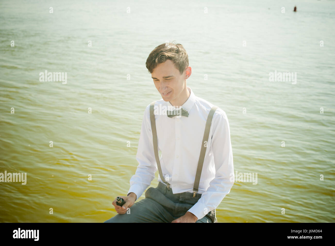 Joven hombre flaco, elegantemente elegantemente vestido con camisa blanca, pantalón  gris con tirantes y pajarita. guy fuma un cigarrillo electrónico, el humo,  la IS Fotografía de stock - Alamy