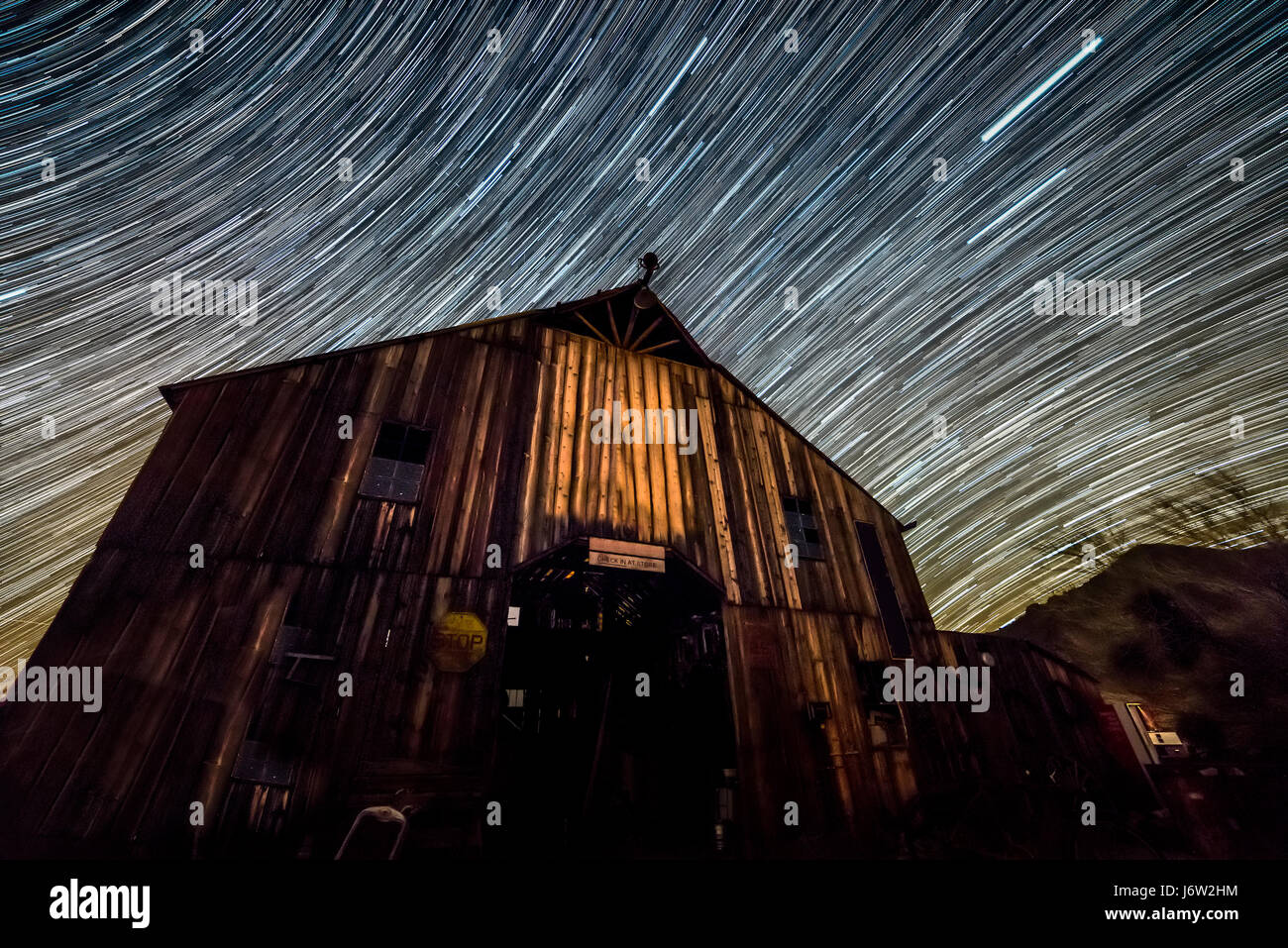 Star trail fotografía captura el camino de las estrellas lejanas sobre un antiguo granero wodden a medida que la tierra gira. Foto de stock