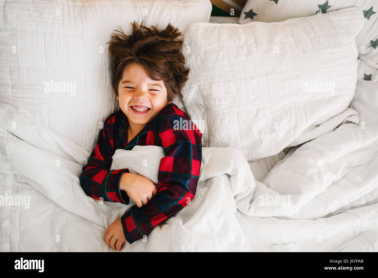 Retrato de un niño acostado en la cama riendo Foto de stock