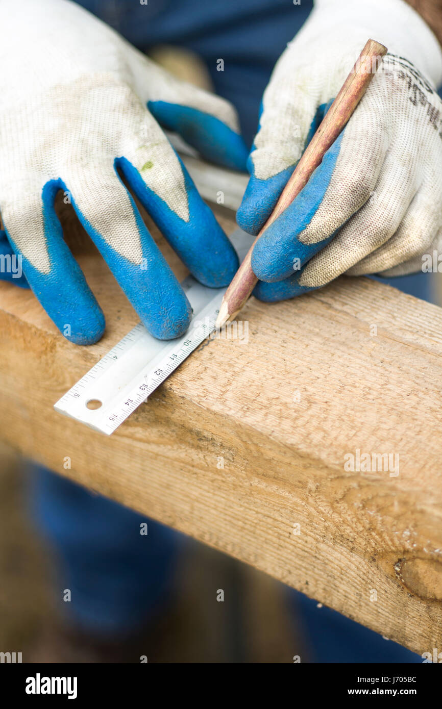 Las manos del carpintero en guantes de protección indican con un lápiz la  dimensión con un ángulo Fotografía de stock - Alamy