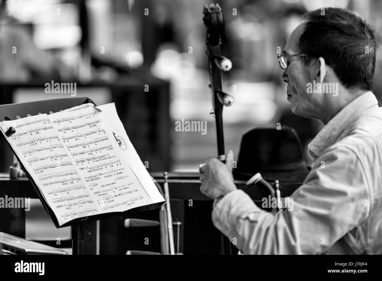 Abril 2017 - Guangzhou, China. La ópera china músico tocando el erhu chino mientras está leyendo partituras. Foto de stock