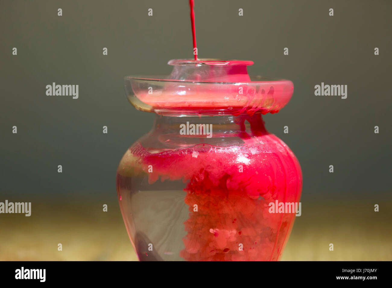 Pintura roja cayendo en el agua en una jarra de vidrio. Foto de stock