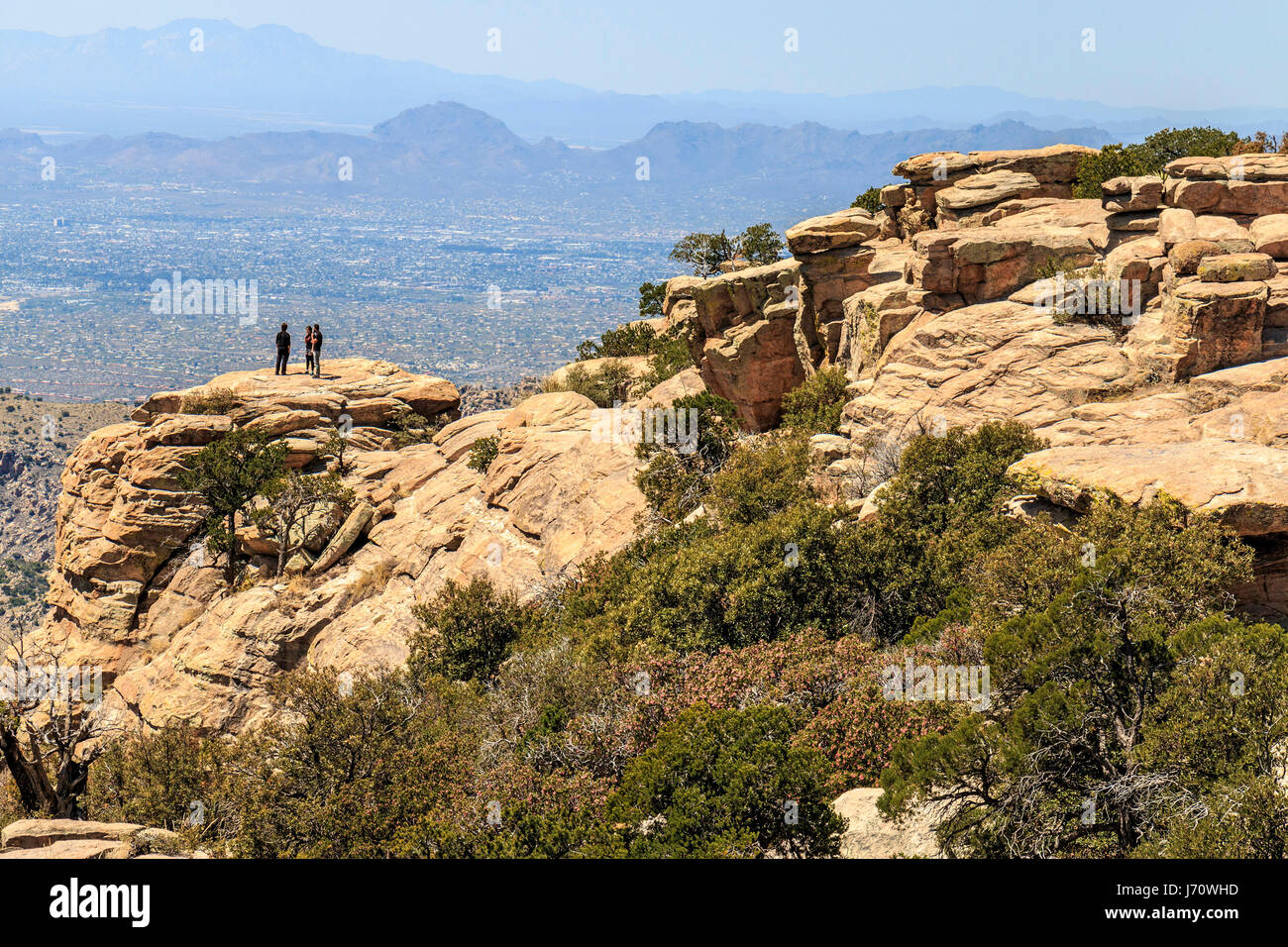 Tres personas, admirar las vistas desde una roca en Windy Point, a lo largo de la carretera hasta monte Lemmon. Con una cumbre de elevación de 9,159 pies (2.792 m), es el hi Foto de stock