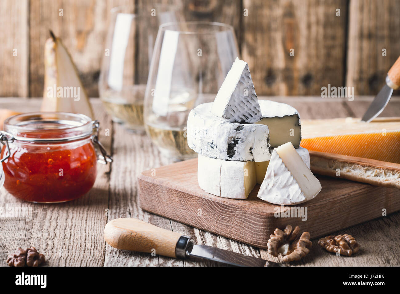 Tabla de quesos servidos con vino blanco, mermelada y nueces sobre