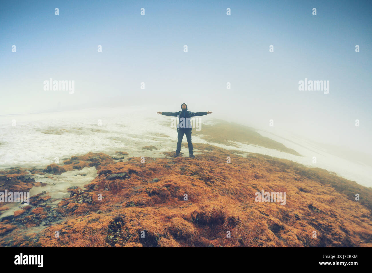 El hombre permanece en libertad turístico plantean en niebla el pico de la montaña Foto de stock