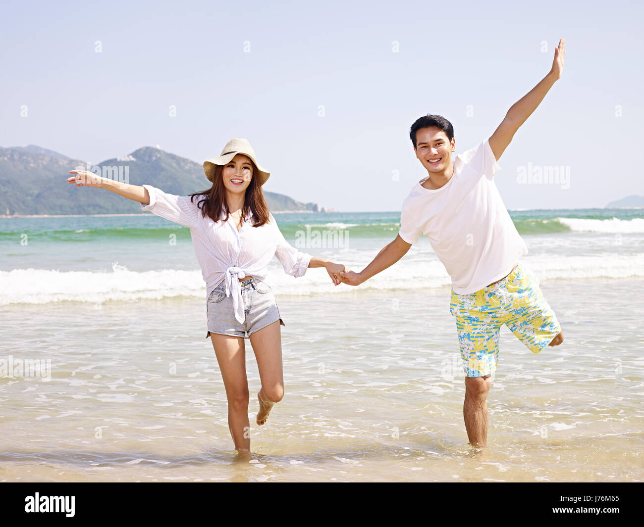 Feliz pareja joven asiático divirtiéndose en la playa. Foto de stock
