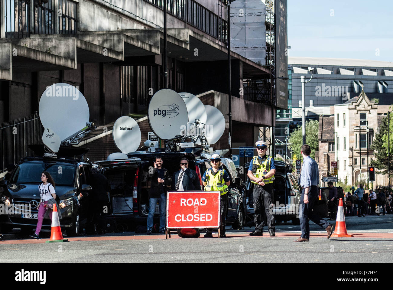 Manchester. 23 de mayo de 2017. La policía haga cumplir un cierre de carretera a raíz del ataque terrorista en Manchester. Los medios de comunicación internacionales que se han reunido para informar sobre la situación y sus satélites vans puede verse en el fondo. Foto de stock