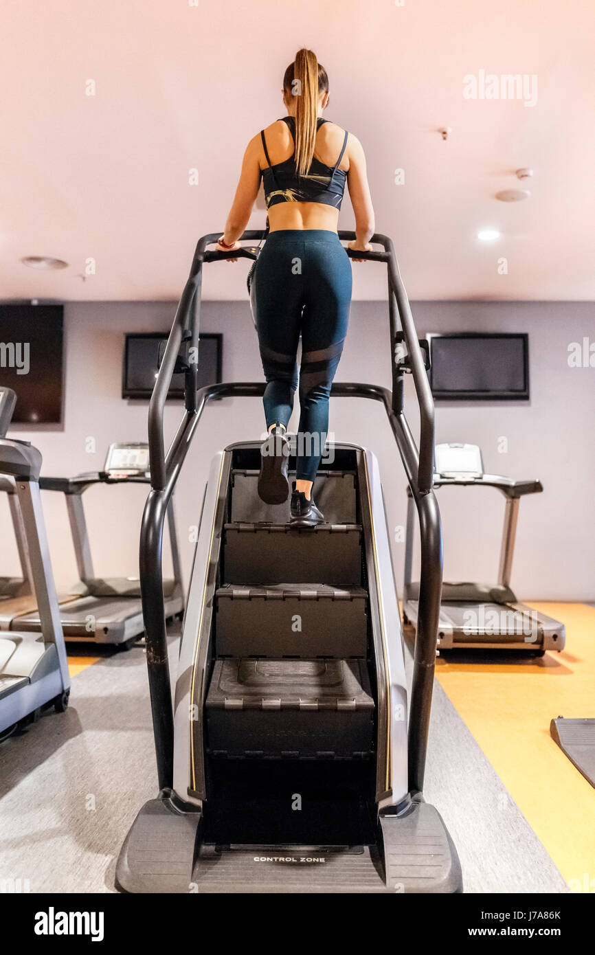 Mujer joven entrenamiento en el gimnasio con una máquina de escaleras  Fotografía de stock - Alamy