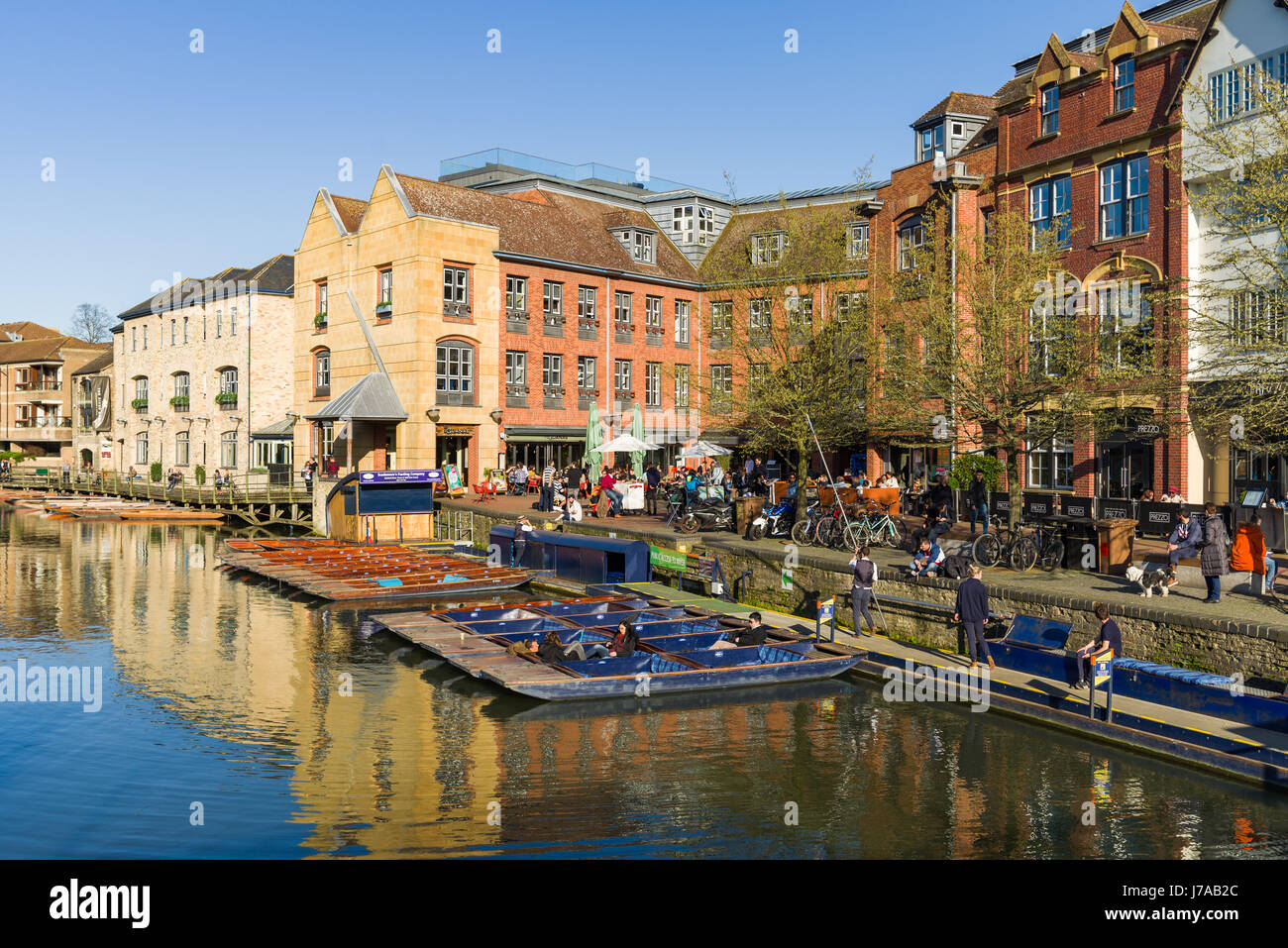 Punt embarcaciones alineadas al borde de los ríos con edificios y personas de antecedentes, Cambridge, Reino Unido Foto de stock