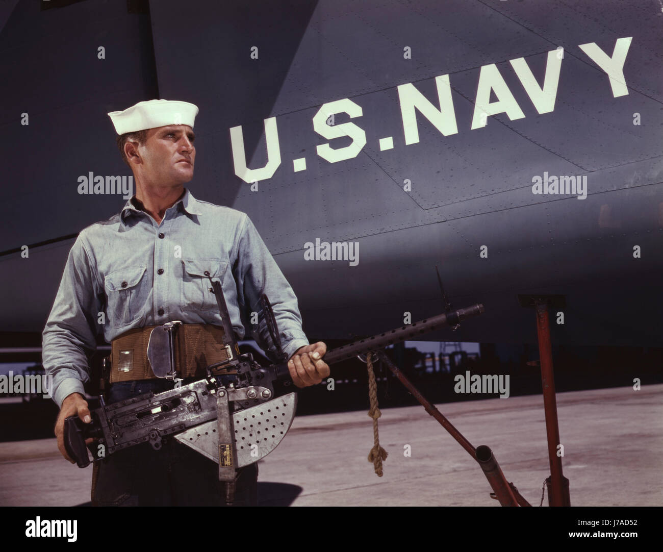 Marinero sosteniendo un .30-ametralladora calibre delante de un avión de la Marina estadounidense, 1942. Foto de stock