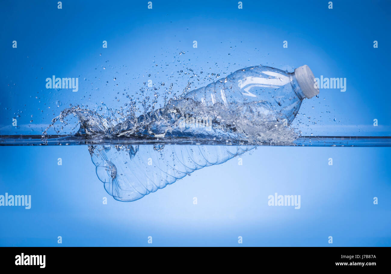 Botella de agua chapoteando en el agua Foto de stock