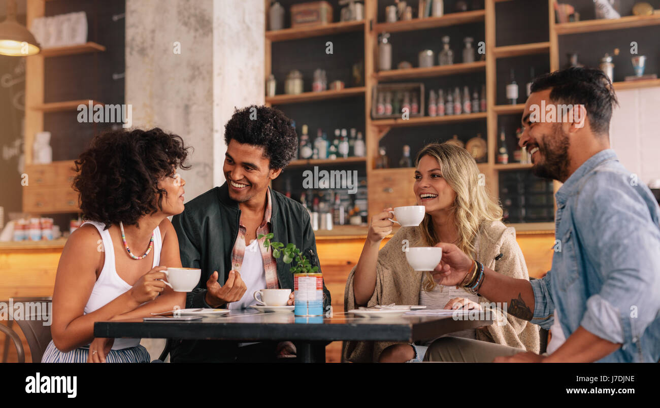 Jóvenes sentados en una cafetería y hablando. Grupo de Amigos juntos  tomando café en una cafetería Fotografía de stock - Alamy