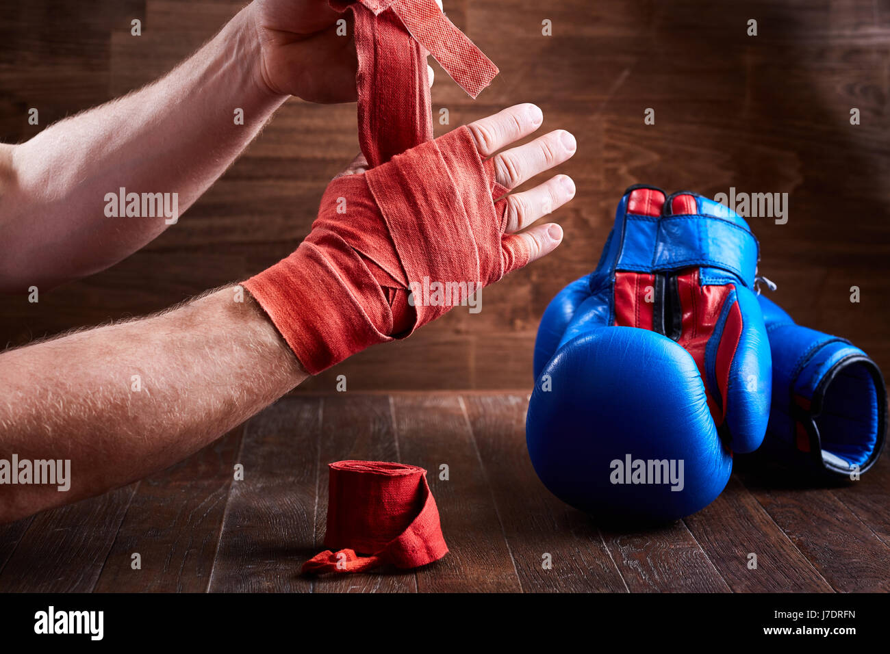 Hombre deportivas envolver su manos con guantes de boxeo y cinta de vendaje  sobre la plancha de madera. La foto en horizontal. Colorido equipo de boxeo.  Boxeo y formación Fotografía de stock 