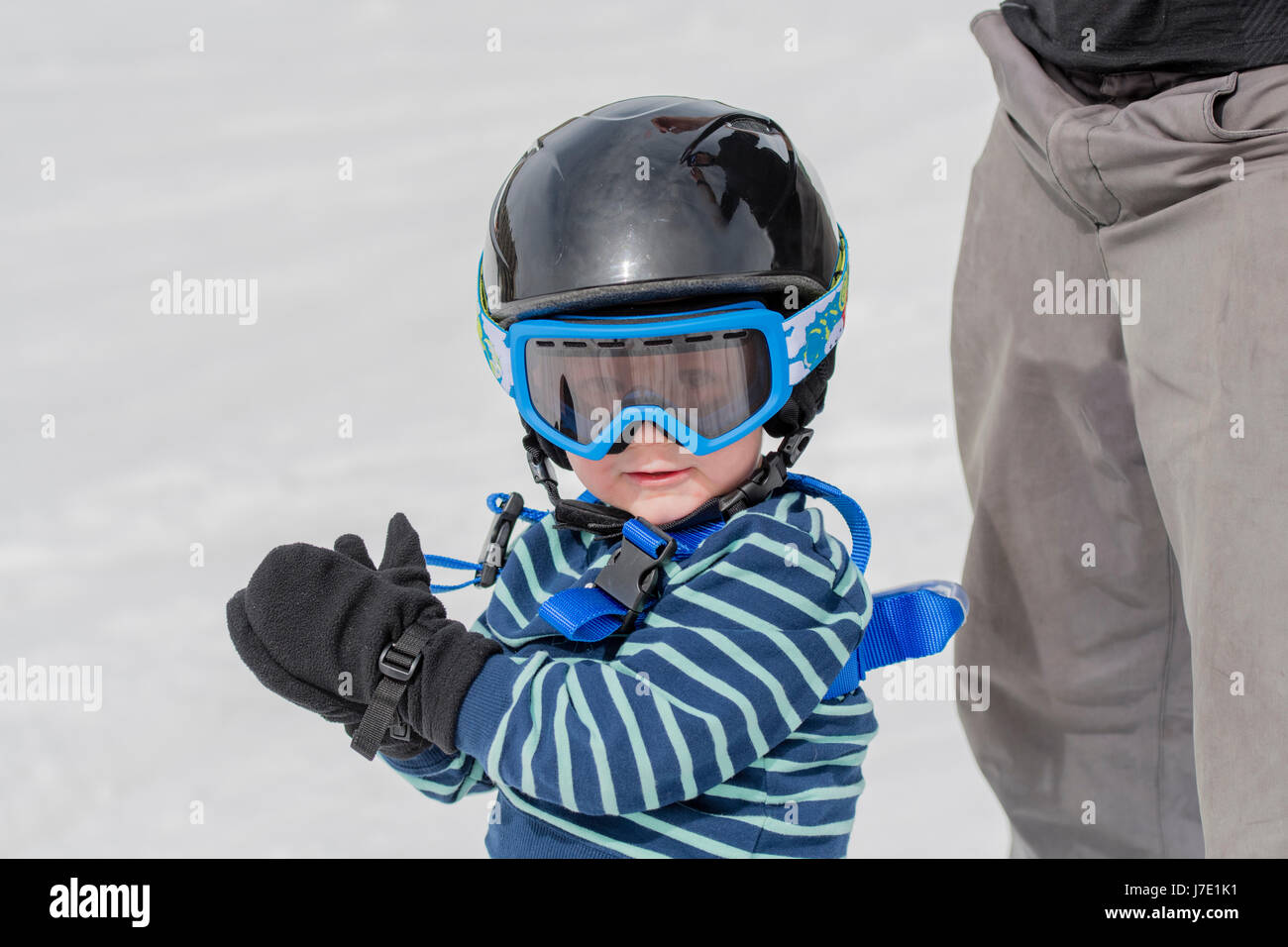 Pequeño niño en ropa de esquí, cascos y gafas, listo para ir a esquiar con  la caída de nieve Fotografía de stock - Alamy