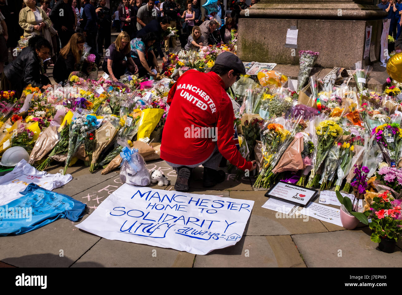 Manchester ataque terrorista. Manchester, Inglaterra, 24 de mayo de 2017. Un hombre en un Manchester United top pone flores en un monumento en Santa Annes Square, el centro de la ciudad de Manchester tras el ataque terrorista en Manchester Arena después de un concierto a cargo de la artista estadounidense Ariana Grande. Foto: Ian Walker / Alamy Live News Foto de stock