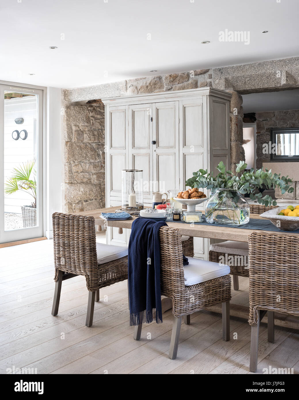 Amplia cocina comedor con paredes de granito expuesta, ratán sillas de comedor y antique cupbaord. Foto de stock