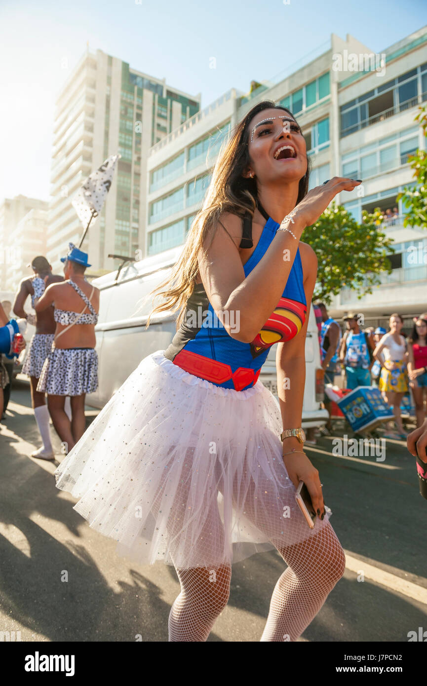 Hermosa mujer brasileña vistiendo coloridos trajes de carnaval y sonriendo  durante el desfile de carnaval en la ciudad.