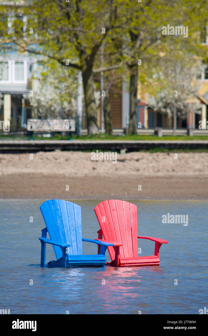 Muskoka sillas parcialmente sumergido en el agua y la arena después de las inundaciones de primavera y gran lago de aguas en Toronto, Ontario, Canadá Foto de stock