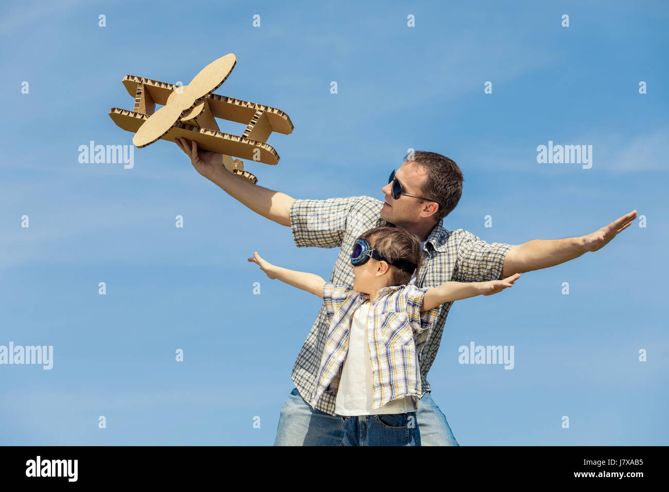 Padre e hijo jugando con el avión de juguete de cartón en el parque por ...
