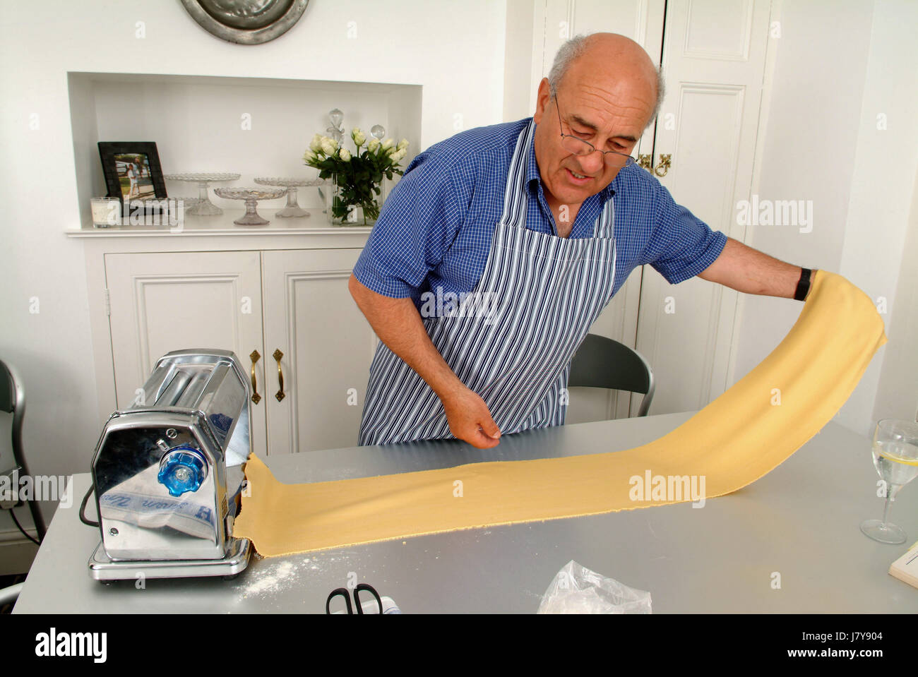 El chef italiano Franco Taruschio hacer hojas de pasta en la cocina de su casa, usando una pasta maker. Foto de stock