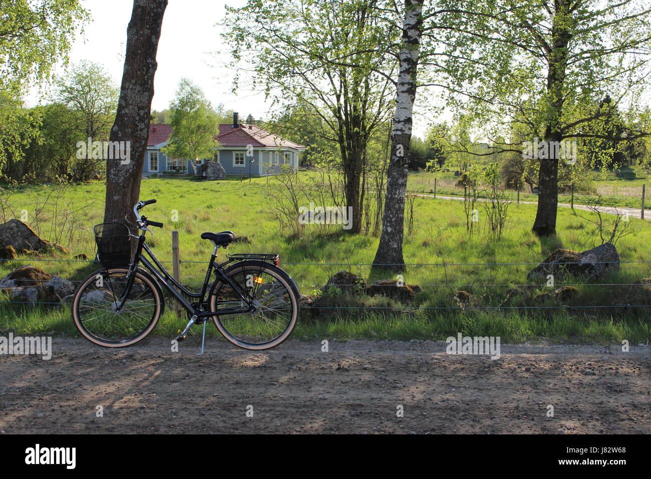 Una bicicleta negra junto a una carretera en un campo sueco vecindario. Foto de stock