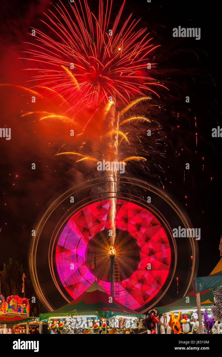 Evergreen State Fair fuegos artificiales con rueda de Ferris y juego de cabinas en la noche Foto de stock